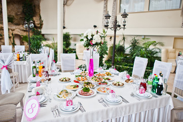 Wedding guest table with flowers and food at wedding hall.