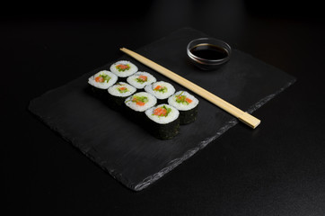 Sushi of norimaki with trout and salad on slate plate