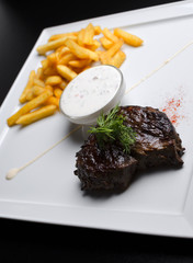 Beef steak with French fries on a white plate