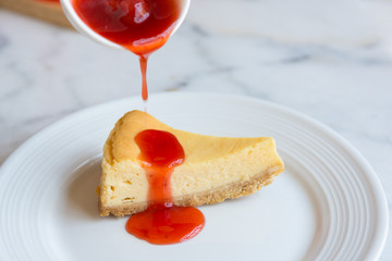 cheese cake with strawberry jam on white dish