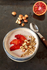 Healthy organic superfood smoothie bowl served with red orange, nuts and oats