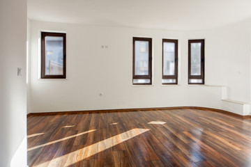 Empty room with natural light from windows.Modern house interior. White walls. Wooden floor.
