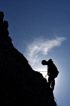 Silhouette of a rock climber hanging on the wall