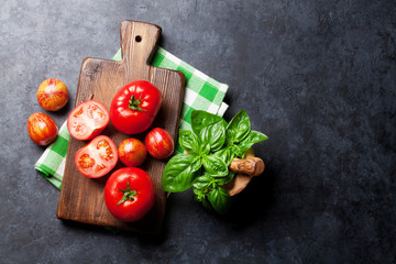 Fresh ripe garden tomatoes and basil on stone table