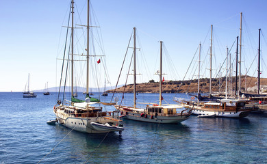 Fototapeta premium Luxury yachts (sailing boats) parked on turquoise water in front of Bodrum castle. The image shows Aegean and Mediterranean culture of coastal lifestyle.