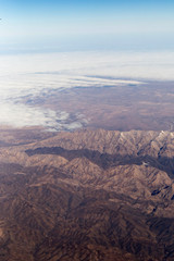 Fototapeta na wymiar Clouds mountains and sky as seen through window of an aircraft of uzbekistan