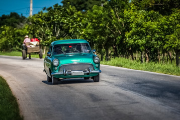 HDR - Oldtimer fährt auf der Landstrasse von Santa Clara in Kuba mit Pferdekutsche im Hintergrund - Serie Kuba Reportage