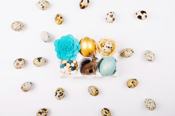 Easter eggs, bunny, candy and  flower in paper tray on white background decoration quail eggs. Flat lay, top view