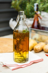 Rosemary Oil in The Glass Bottle on Folded Napkin with Fresh Rosemary inside.