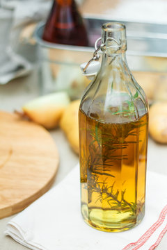 Rosemary Oil in The Glass Bottle on Folded Napkin with Fresh Rosemary inside.