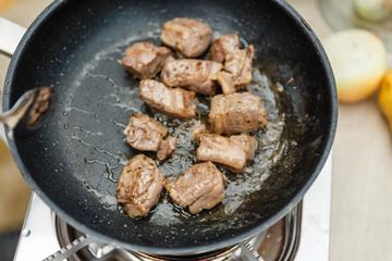 Chef Fried Marinated Diced Raw Beef in Pan with Rosemary Oil with Spoon.