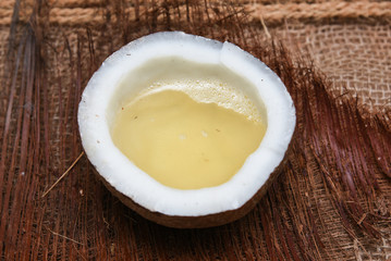Extra virgin edible coconut oil / copra oil in a half cut coconut on jute coir background Kerala, India. used for cooking, massage in spa and ayurveda