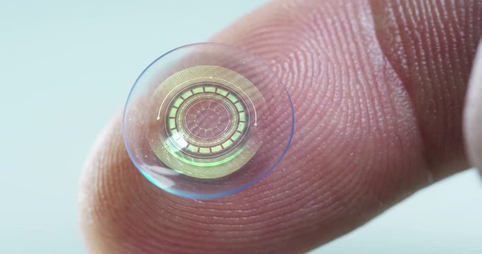Macro shot of a finger holding a contact lens technology with a chip to see better in both eyes and increase diopters. Concept: eye examination, optical, immersive technology