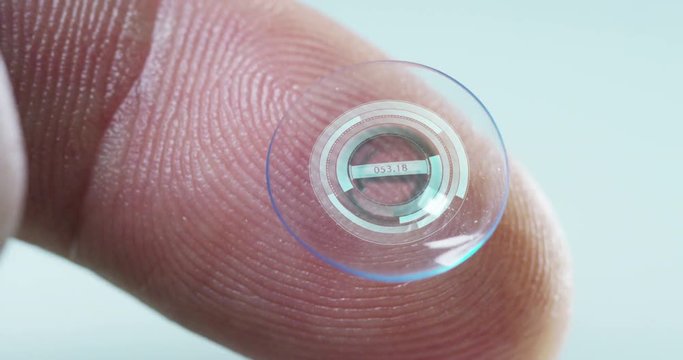 Macro shot of a finger holding a contact lens technology with a chip to see better in both eyes and increase diopters. Concept: eye examination, optical, immersive technology