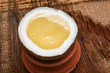Extra virgin edible coconut oil / copra oil in a half cut coconut on jute coir background Kerala, India. used for cooking, massage in spa and ayurveda