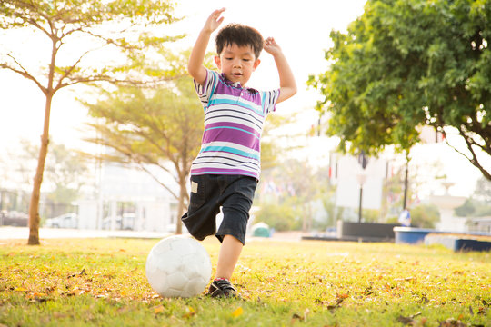 Boy Learning Kick Ball At The Park In The Evening