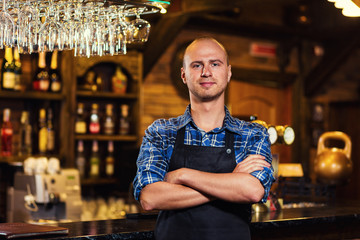 Barman at work in pub,Portrait of cheerful barman worker standing,Waiter giving menus,A pub.Bar.Restaurant.Classic.Evening.European restaurant.European bar.American restaurant.American bar.