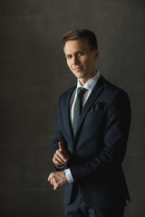 Handsome businessman in black formal suit on gray background