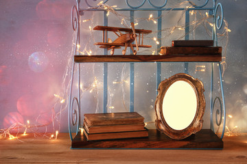 Vintage shelf with old wooden plane toy, books and blank photo frame