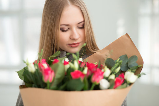 Woman looking at white and pink roses bouquet in studio