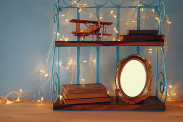 Vintage shelf with old wooden plane toy, books and blank photo frame