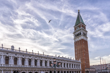 A bird flies over Piazza San Marco, the historic center of Venice, Italy, against a beautiful sky