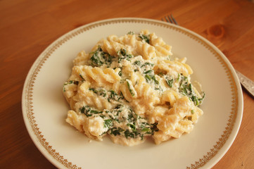 Fusilli pasta with spinach and ricotta on plate with wood background