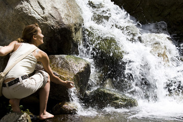 femme souriant accroupie au bord d'une cascade