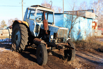 An old broken rusted tractor in the Russian village against a blue sky - Powered by Adobe
