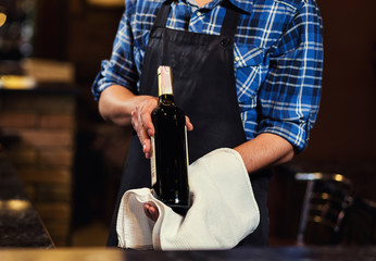 Bartender offers wine,Barman at work in pub,Portrait of cheerful barman worker standing,A pub.Bar.Restaurant.Evening.European restaurant.European bar.American restaurant.American bar.