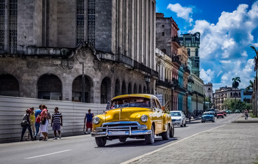 Fototapeta na wymiar HDR - Kuba amerikanische gelber Chevrolet Oldtimer fährt auf der Hauptstrasse von Havanna City in Kuba- Serie Kuba Reportage