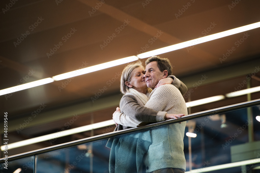 Wall mural Senior couple standing at the train station, waiting, kissing