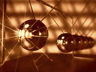 vintage Newton's cradle with broken glass, silver cradle on dark surface