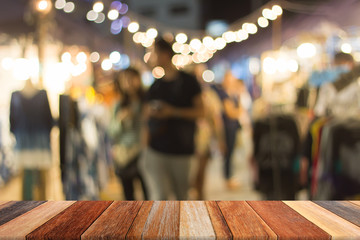Blurred people shopping on night market on wood table