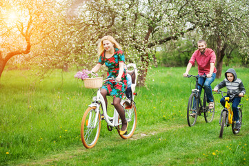 Fototapeta premium Happy family on a bicycles in the spring garden