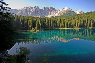 Fototapeta na wymiar Lago di Carezza, an extremely clear lake in the Dolomites of Northern Italy. Visibility more than 30 feet down to see logs, fish and sand. Also known as Rainbow Lake.