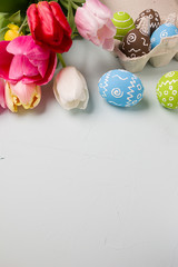Painted easter eggs and bouquet of spring tulips closeup on a light blue background with space for congratulation