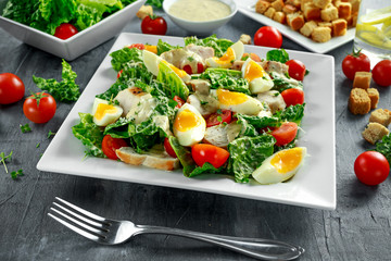 Fresh healthy Caesar salad with chicken, eggs, tomatoes, Cheese and Croutons on white plate