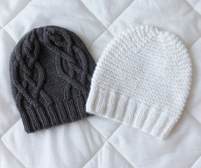 Hats black and beige colors on a rag background, knitted wool by hand on the spokes