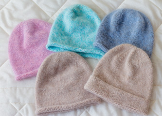 Caps of different colors on a rag background, knitted wool by hand on the spokes