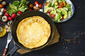 Omelette in a pan with vegetables salad, mushrooms, radish and spices