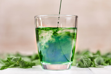 Green chlorophyll drink in glass with water - obrazy, fototapety, plakaty