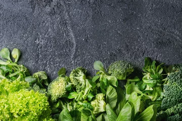 Photo sur Plexiglas Légumes Variety of raw green vegetables salads, lettuce, bok choy, corn, broccoli, savoy cabbage as frame over black stone texture background. Top view, space for text