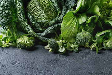 Tableaux sur verre Légumes Variety of raw green vegetables salads, lettuce, bok choy, corn, broccoli, savoy cabbage as frame over black stone texture background. Space for text