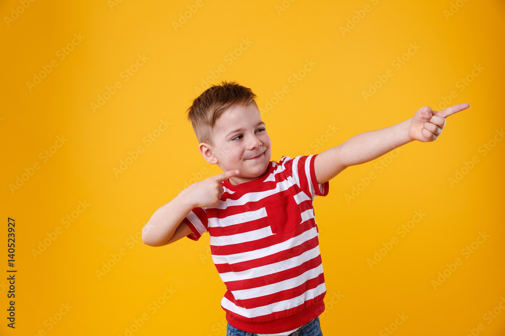 Wall mural Portrait of a funny little kid pointing fingers away