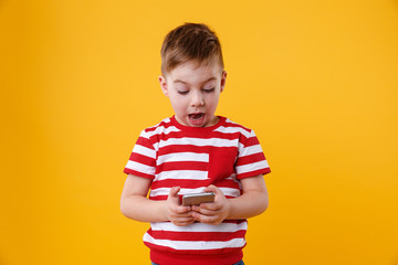 Naklejka premium Clever excited little boy reading message on mobile phone