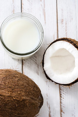 Coconut and coconut milk on white wooden table
