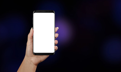Woman holding smart phone with white screen for mockup. Black background with purple bokeh.