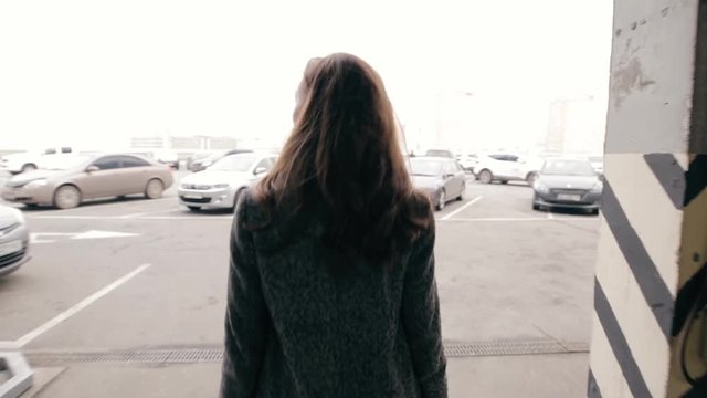 Young woman walking in a parking - back view