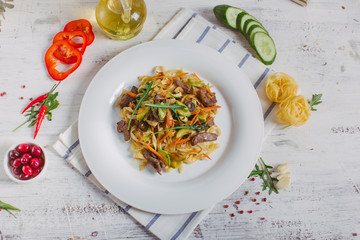 Pasta with olive meat greens on a white plate